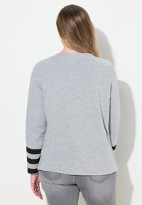 Grijze katoenpullover met een ronde halslijn en lange mouwen, met zwarte strepen op de manchetten. Soepele textuur met een relaxte pasvorm.