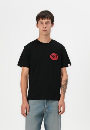 Black cotton short-sleeve t-shirt featuring a red circular graphic with "981 REPLAY" text. The fit is relaxed, with a tag on the left sleeve.