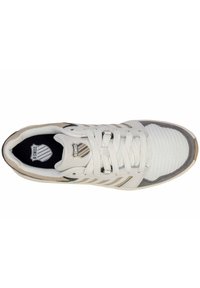 Zapatilla blanca con superposiciones de malla y cuero, acentos grises y logo negro. Presenta un cierre con cordones y un colorín acolchado para mayor comodidad.
