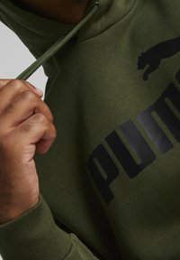 Grön huvtröja i mjukt tyg, med svart "PUMA"-logotyp och katt-silhuett, justerbar dragsko och ribbade ärmar.