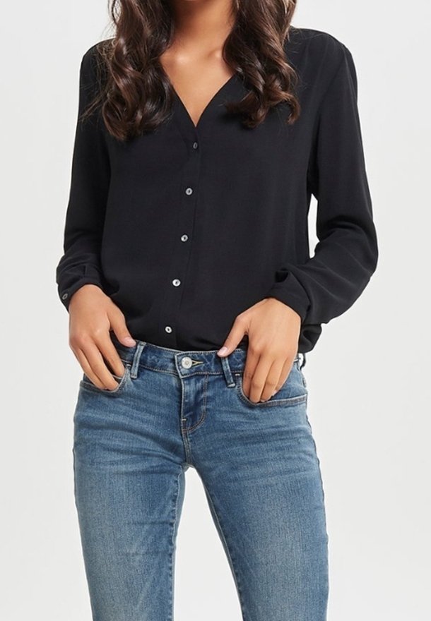 Maglietta nera a maniche lunghe con chiusura a bottoni e scollatura a V, in tessuto morbido e con bottoni a contrasto, abbinata a jeans in denim blu.