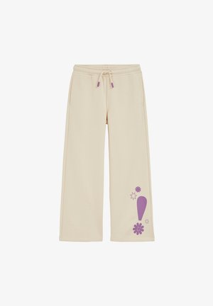 Pantaloni sport bej din material moale, cu un design grafic mov, având un motiv floral și accente stelare pe partea inferioară stângă.