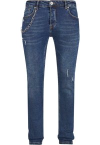 Sötétkék farmernadrág slim fit szabással, kopott részletekkel és ezüst lánc díszítéssel a bal zsebén, valamint hagyományos övfogókkal.