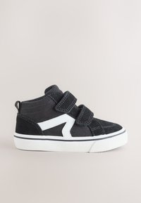 Zwarte peutersneaker met witte zool, twee klittenbandsluitingen en een wit zigzagdetail aan de zijkant, tegen een effen lichte achtergrond.
