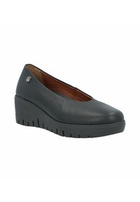 Zapato de cuña de cuero negro con punta redonda, suela de goma gruesa y texturada, y un pequeño detalle metálico.
