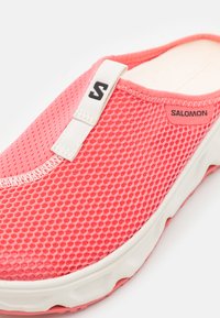 Chaussure slip-on Salomon, avec un dessus en mesh rose respirant, une semelle en caoutchouc blanc et des accents neutres. Comprend une étiquette de marque pour un enfilage facile.