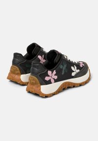 Black athletic shoes with floral designs in pink and green, textured fabric, cushioned white midsole, and a rugged brown outsole.