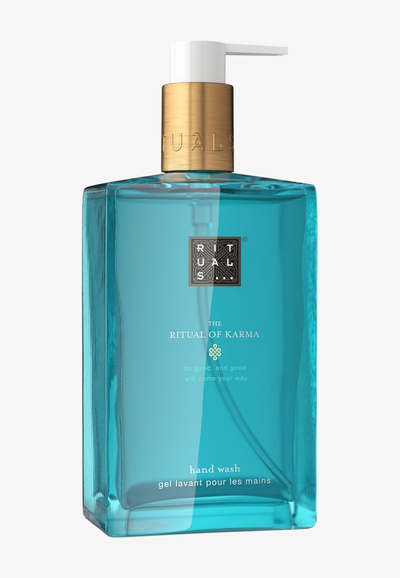 Een heldere turquoise glazen fles met een gouden pompd dispenser, gelabeld "The Ritual of Karma," met gestructureerde accenten en meertalige tekst.