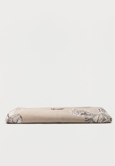 Tissu beige plié avec un motif floral foncé, présenté à plat sur un fond blanc.