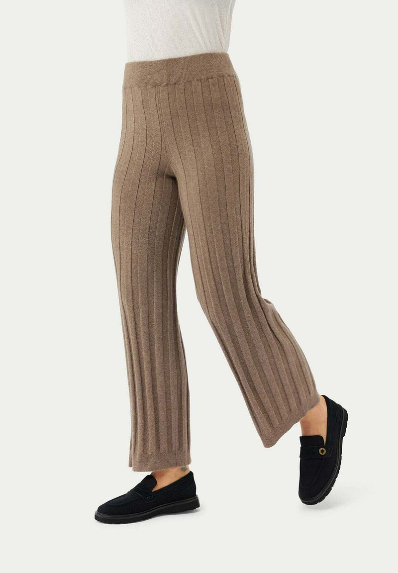 Braune, gerippte Strickhosen mit einem breiten Bund und ausgestellt geschnittenen Beinen, kombiniert mit schwarzen Schlupfschuhen mit einem kleinen dekorativen Akzent.