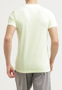 Camiseta de manga corta color amarillo claro, hecha de tela texturizada, con cuello redondo y ajuste relajado, diseñada para comodidad y transpirabilidad.