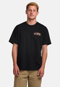 Black cotton t-shirt with short sleeves, featuring a multicolored graphic logo on the left chest. The fabric appears smooth and untextured.