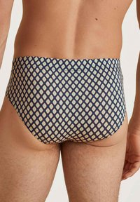Costumi da bagno con un design aderente, caratterizzati da uno sfondo blu navy e un motivo a rombi in crema e azzurro chiaro. Realizzati in materiale elastico.
