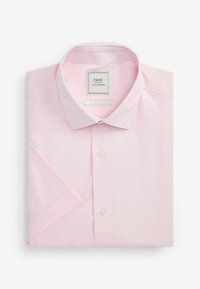 Chemise habillée rose clair à manches courtes soigneusement pliée avec un col classique et des boutons blancs.