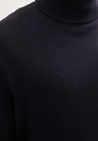 Suéter de cuello alto negro hecho de una suave tela de punto, con un diseño ajustado y textura acanalada. Sin patrones ni acentos visibles.