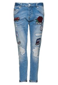 Ljusblå denimjeans med slim fit, med slitna områden och olika lappar, inklusive en ros och grafiska textaccenter.