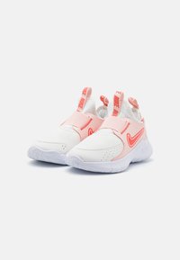 White athletic shoes with a textured upper, featuring pink accents and a prominent Nike logo. Slip-on design with loop straps.