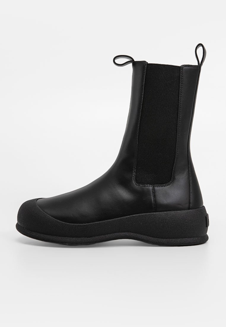 Czarne botki za kostkę wykonane ze skóry i teksturowanej tkaniny. Posiadają okrągły czubek, elastyczne boki, gumową podeszwę oraz pętelkę z tyłu.