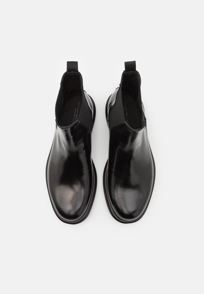 Botas Chelsea de charol negro con paneles laterales elásticos y tiradores, con una punta redondeada elegante y un acabado liso y brillante.