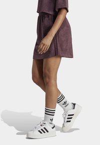 Lila överdimensionerad klänning med korta ärmar, med ett elastiskt midjeband. Kombinerad med vita sneakers och svartsrandiga strumpor.