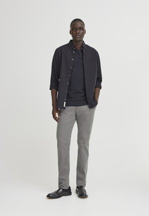 Casual outfit featuring a black button-up shirt, a dark t-shirt underneath, gray pants, and black leather shoes. Simple design, fitted silhouette.