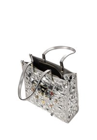 Bolso tote plateado con grandes lentejuelas y pines coloridos, con dos asas superiores y un compartimento interior abierto con cremallera.