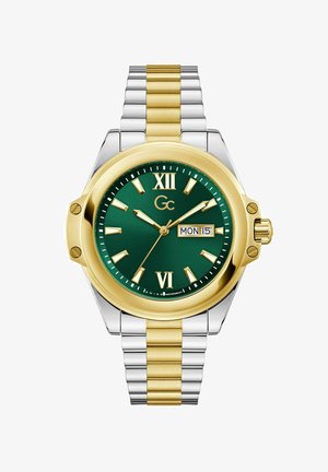 Zaļš ciparnīca pulkstenis ar zelta un sudraba toni nerūsējošā tērauda siksnu. Romiešu cipari pie 12 un 6, datuma rādītājs un zelta akcenti uz rādītājiem.