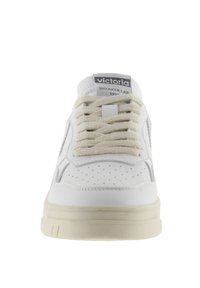 Baskets en cuir blanc avec un bout perforé, lacets crème, accents gris sur les côtés et une semelle en caoutchouc épaisse. L'étiquette indique "Victoria Sneaker Lab."