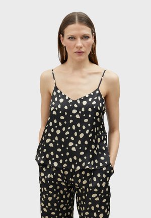 Zwarte satijnen camisole met een gelaagd ontwerp en een crèmekleurig stippenpatroon. Voorzien van dunne verstelbare bandjes en een V-halslijn.