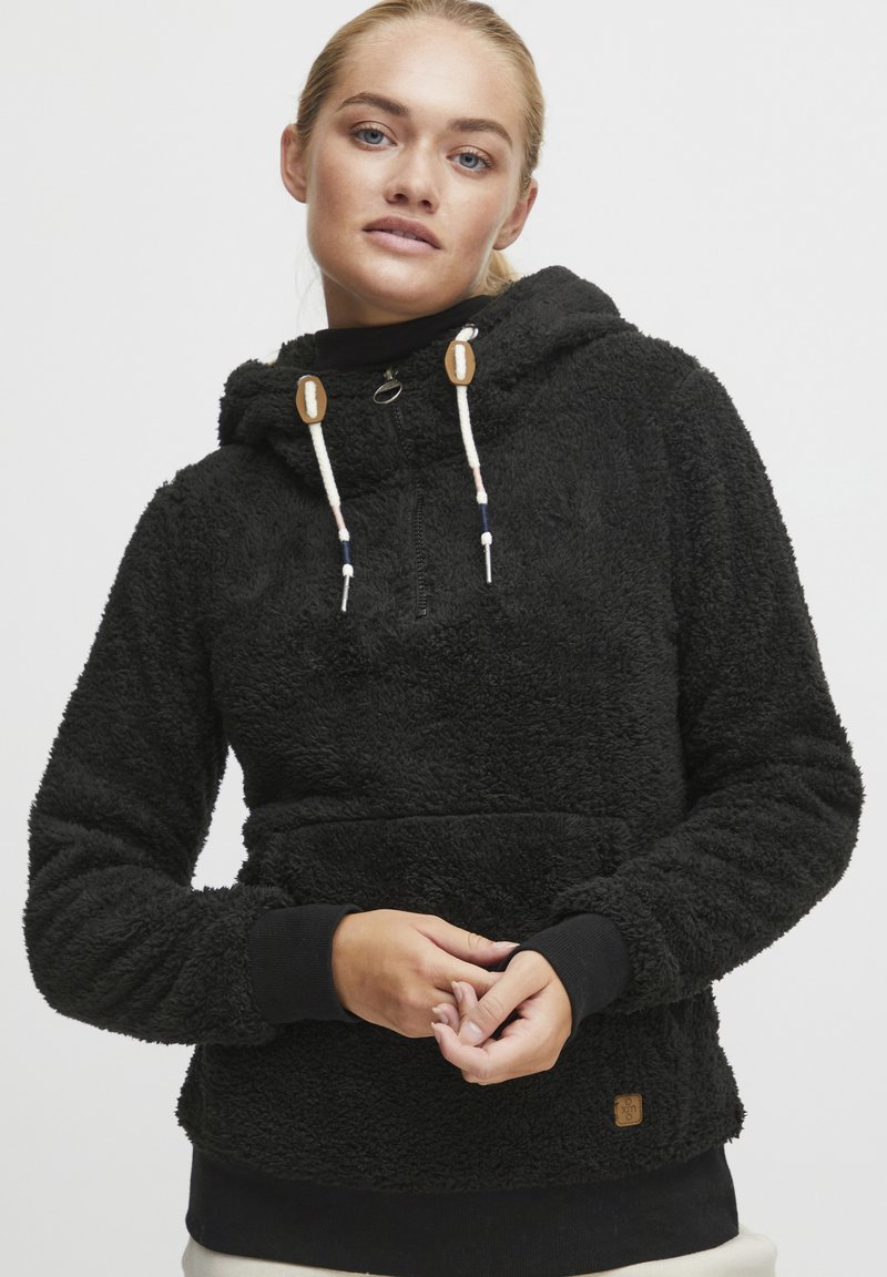 Sudadera de forro polar negra con media cremallera, cordones ajustables, bolsillo frontal y un acabado texturizado. Presenta puños y bajo acanalados.
