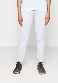 Svetle šedé tepláky vyrobené z měkké látky, s tapered designem, elastickými manžetami a odpovídajícími akcenty. Nosit s černými sportovními botami.