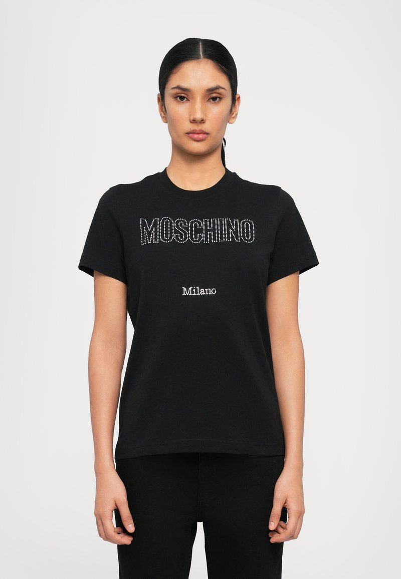 Melnas kokvilnas t-krekls, kurā ar rhinestones ir uzrakstīts "MOSCHINO", bet zem tā mazākā tekstā "Milano". Klasisks apaļais kakls un īsas piedurknes.