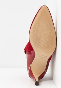 Chaussure à talon haut en daim rouge avec bout pointu et semelle texturée. Comprend un accent en cuir lisse et un petit talon. Taille 37.