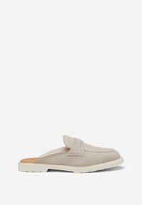 Mule en daim beige clair à enfiler avec semelle blanche basse et détail de bride cousue sur le dessus, vue de côté sur fond blanc.