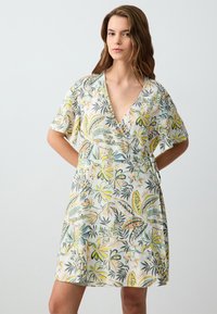 Abito avvolgente floreale in tessuto leggero con scollo a V, maniche corte e un motivo vivace con accenti gialli, verdi e corallo.