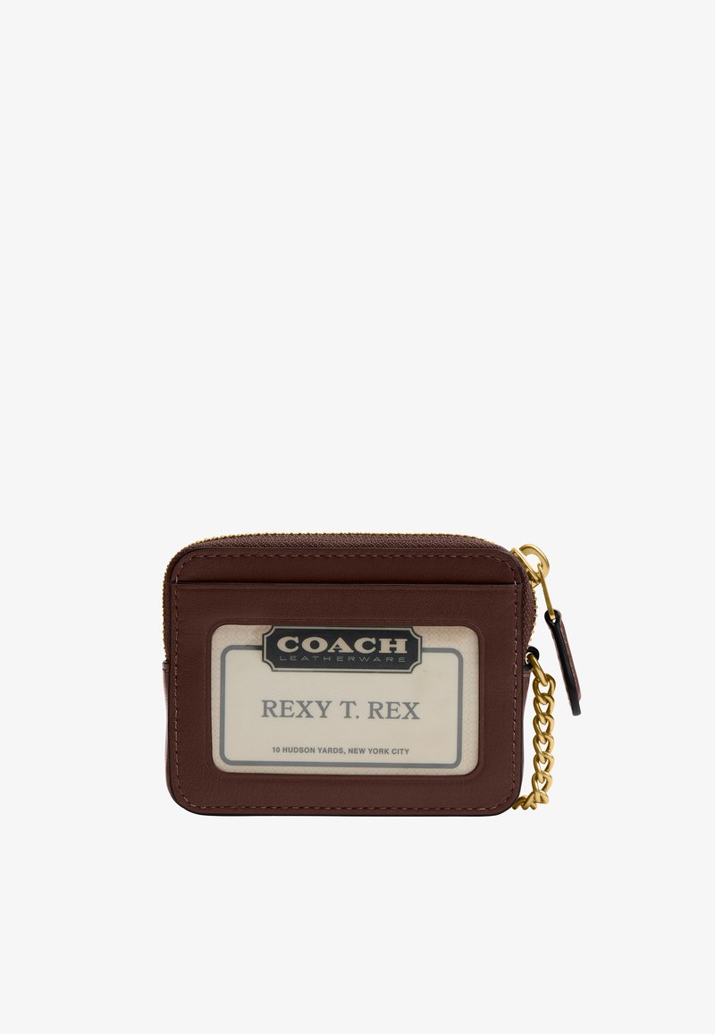 Porte-cartes Coach en cuir marron avec fenêtre d’identification transparente affichant "REXY T. REX" et détails de fermeture éclair et chaîne dorés sur fond blanc.