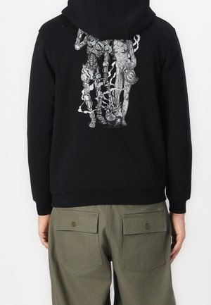 Sweat à capuche noir avec un motif blanc représentant une silhouette squelettique et un humanoïde partiellement décomposé debout côte à côte, émettant de la fumée ou des flammes.