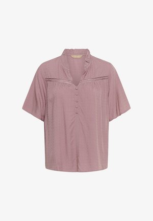 Ružova bluzica s kratkimi rokavi in volančastim ovratnikom, spredaj na gumb, z vzorcem teksturiranih pik. Ima horizontalni trak z metalnimi detajli.