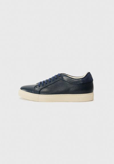 Marineblauwe leren sneaker met een crèmekleurige rubbersole, voorzien van blauwe veters en een gladde textuur. Ronde neus en minimalistisch ontwerp.