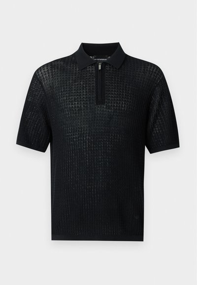 Polo en maille noire à manches courtes avec motif côtelé vertical et fermeture éclair partielle au col.