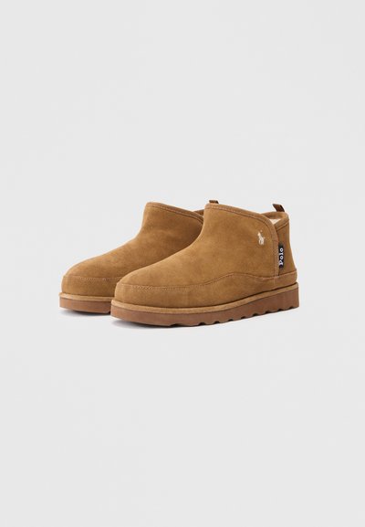 Botine negre din suede cu vârf rotunjit, suprafață texturată și talpă din cauciuc. Dispune de o bandă de prindere la spate și un detaliu mic cu logo.