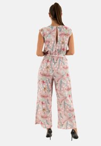 Mono floral en rosa y gris con grandes lunares, mangas cortas, abertura en la espalda, cintura con cinturón y diseño de pierna ancha. Textura de tela suave.