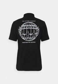 Polo noir à manches courtes avec un graphique blanc représentant des figures interconnectées autour d'un globe, accompagné des phrases "L'AVENIR EST PROMETTEUR" et "ENSEMBLE NOUS RÉUSSISSONS".