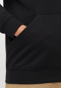Zwarte sweatshirt met een geribbelde onderrand en manchetten, voorzien van een kangoeroezak aan de voorkant. Vlotte textuur en comfortabele pasvorm.