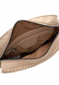 Interno di una borsa di pelle beige con tasca con zip, rivestimento morbido e texture intrecciata lungo il bordo. Design compatto e funzionale.