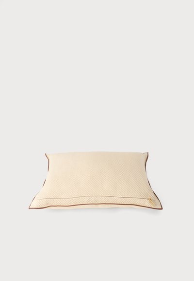 Coussin rectangulaire beige avec une texture subtile et un passepoil marron le long des bords sur un fond blanc uni.