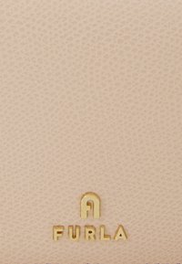 Rosa Lederbörse mit strukturierter Oberfläche und goldenen "FURLA"-Logo in fetter Schrift am unteren Rand.