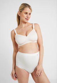 Beige borstvoedingsbh met verstelbare straps en zachte cups, gecombineerd met witte hooggewaisted onderbroek met kantafwerking en een klein accentdetail.