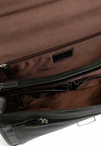 Black leather bag interior with a brown fabric lining, featuring one zipped pocket and an open compartment with a textured pattern.