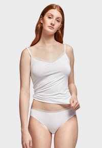 Witte katoenen top met dunne bandjes en een V-halslijn, gecombineerd met witte slipjes met een delicate scalloped tailleband.